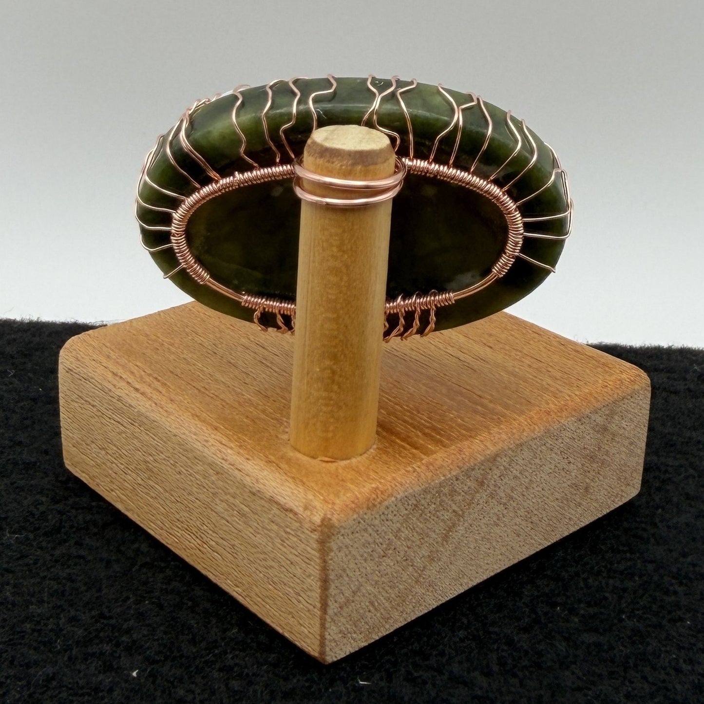 Back view of a tree of life display piece featuring a green serpentine stone with copper wire roots and branches and a white moon, mounted on a square wooden display block.