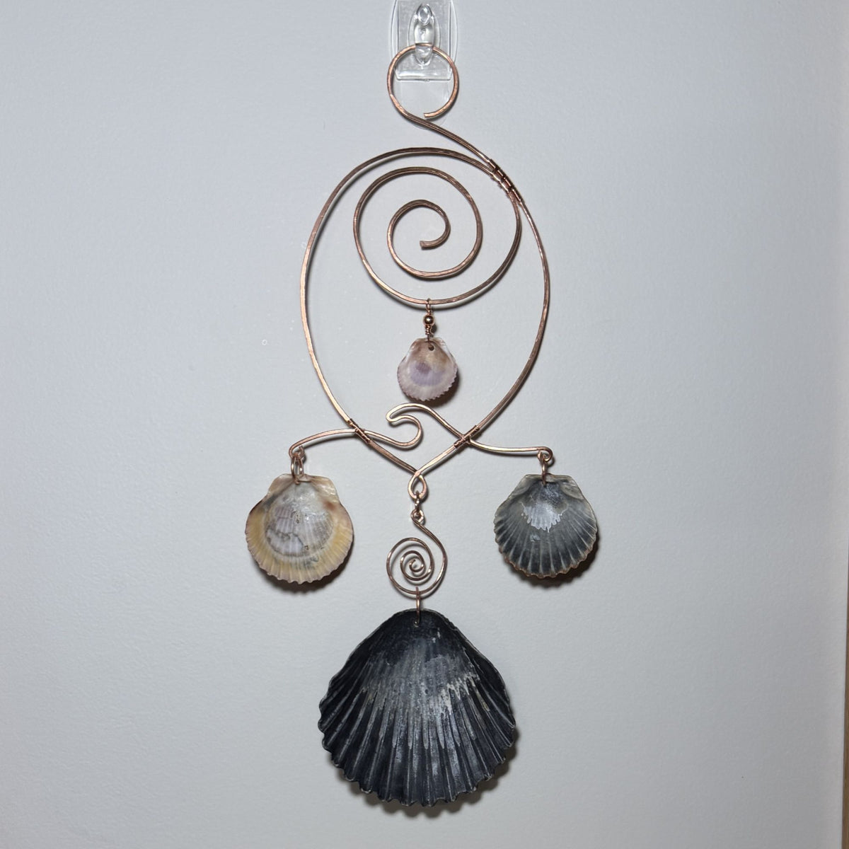 Back view of a shell and hammered copper wire wall/window display piece.