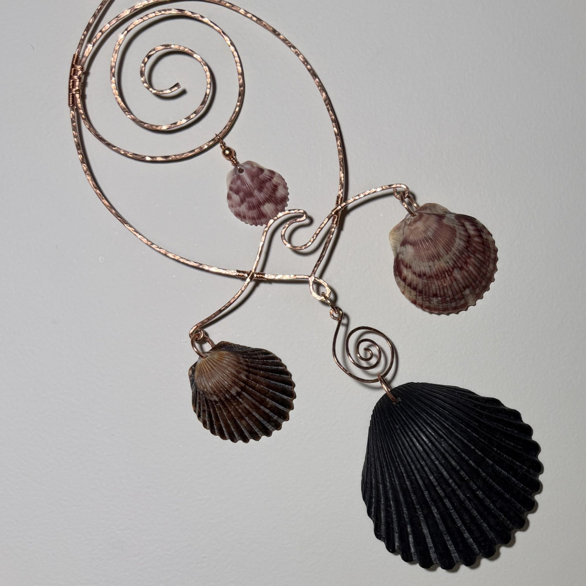 Detail view of a shell and hammered copper wire wall/window display piece.