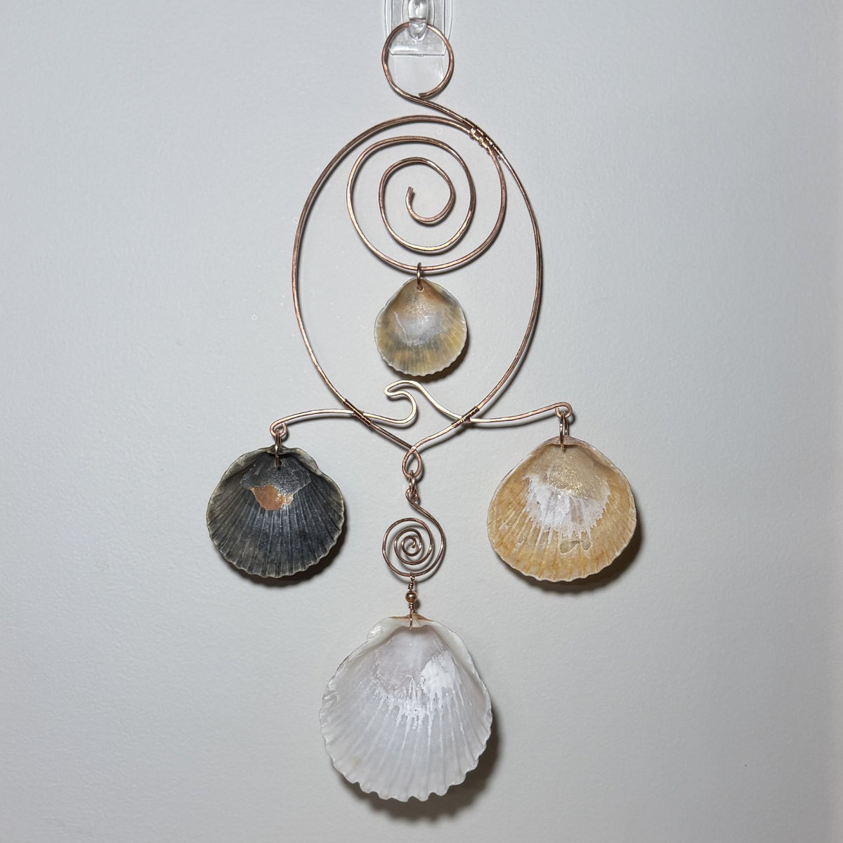 Back view of a shell and hammered copper wire wall/window display piece.