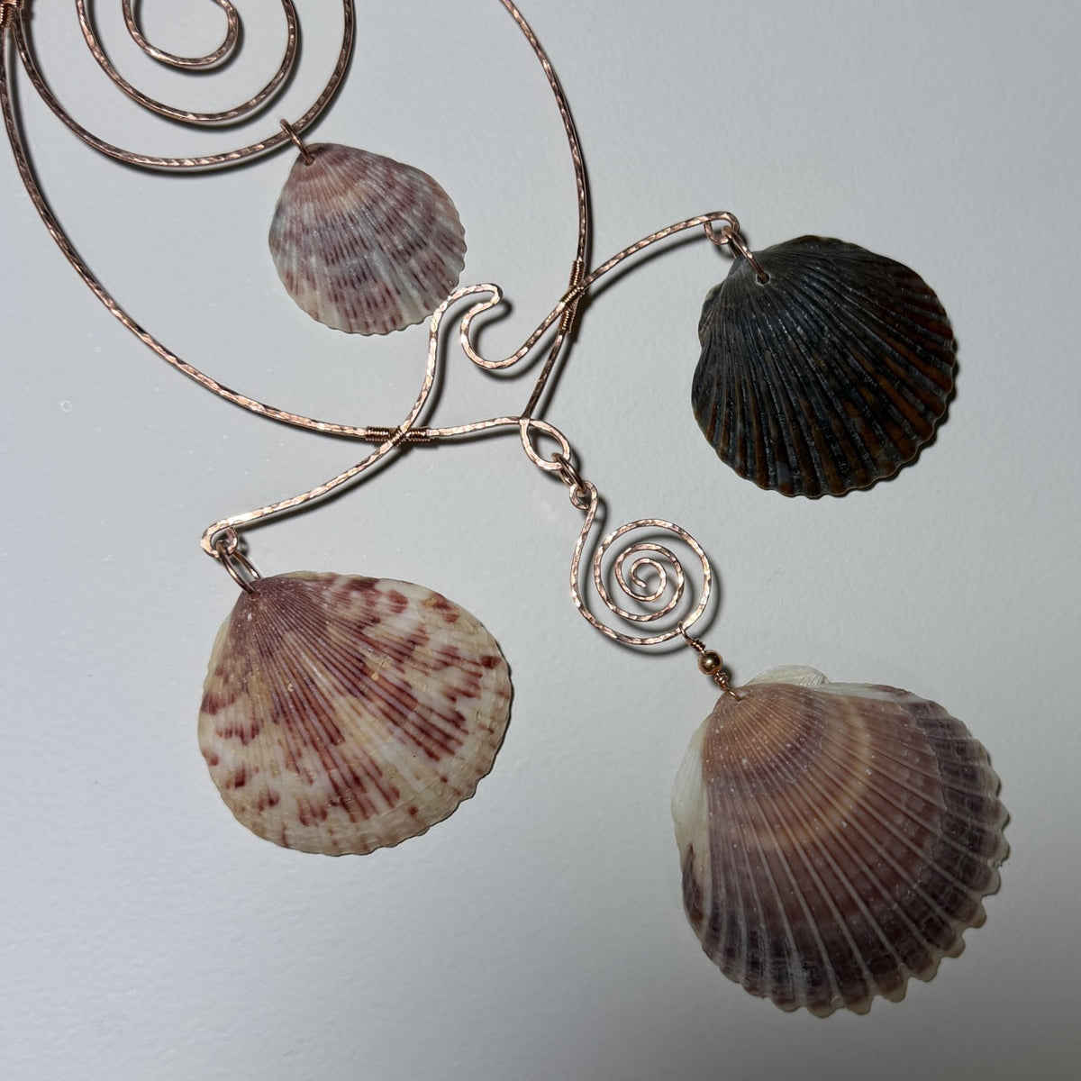 Detail view of a shell and hammered copper wire wall/window display piece.