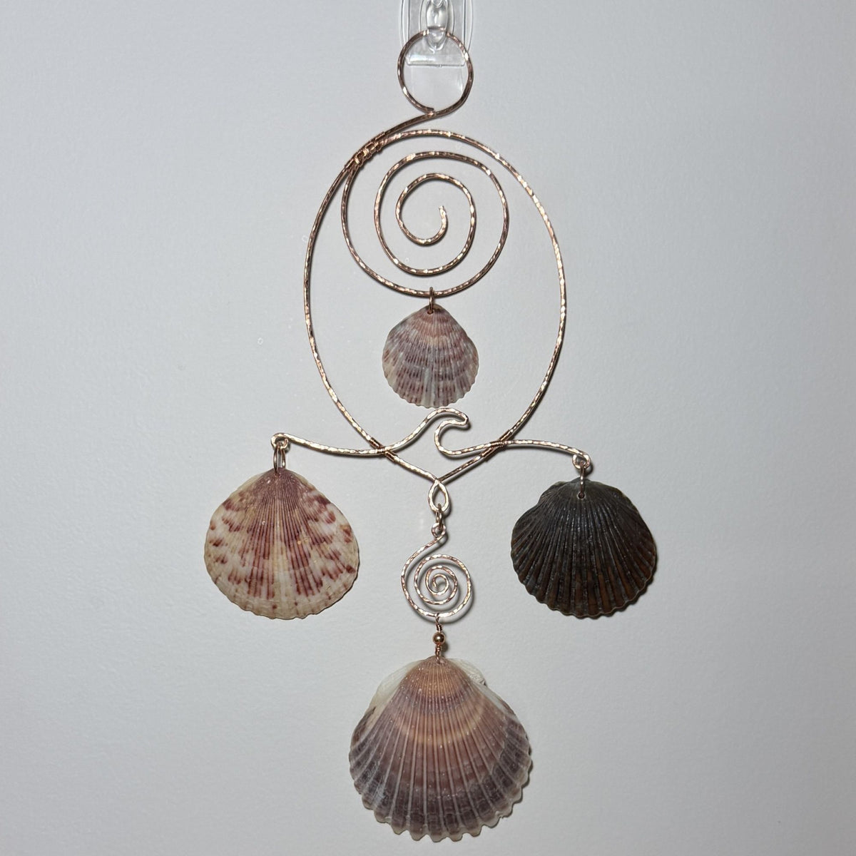 Front view of a shell and hammered copper wire wall/window display piece.