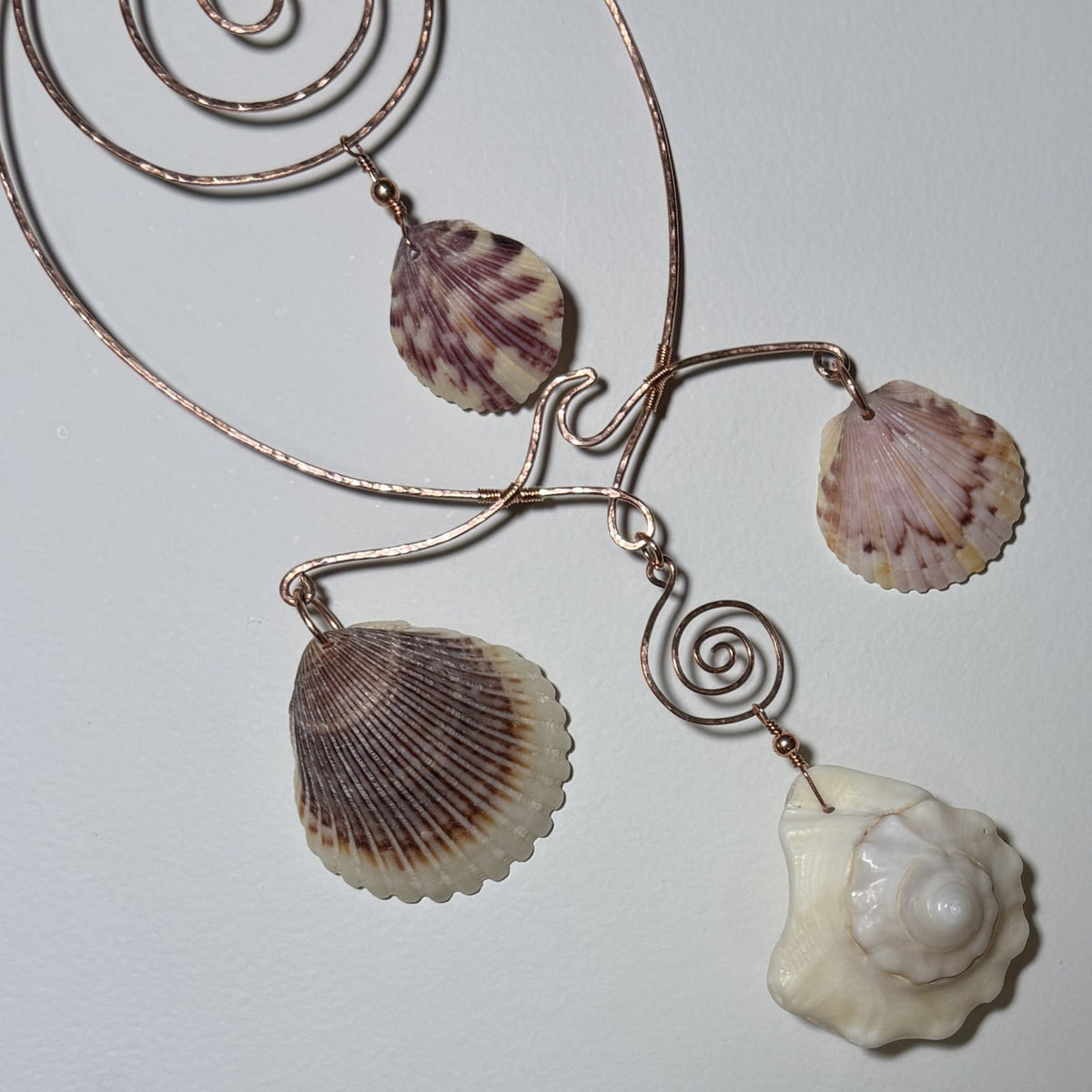 Detail view of a shell and hammered copper wire wall/window display piece.