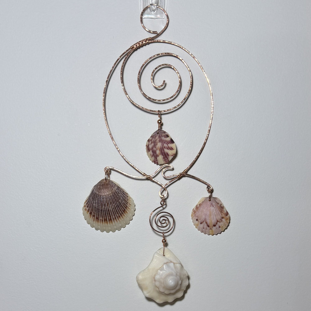 Front view of a shell and hammered copper wire wall/window display piece.