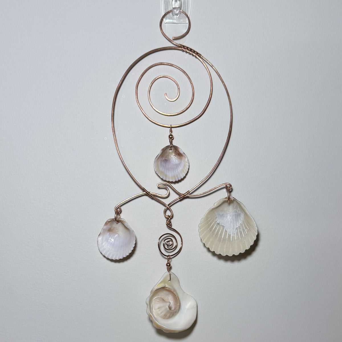 Back view of a shell and hammered copper wire wall/window display piece.