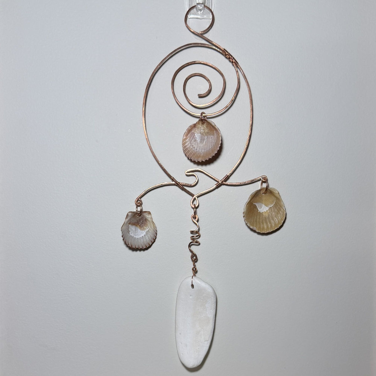 Back view of a shell and hammered copper wire wall/window display piece.