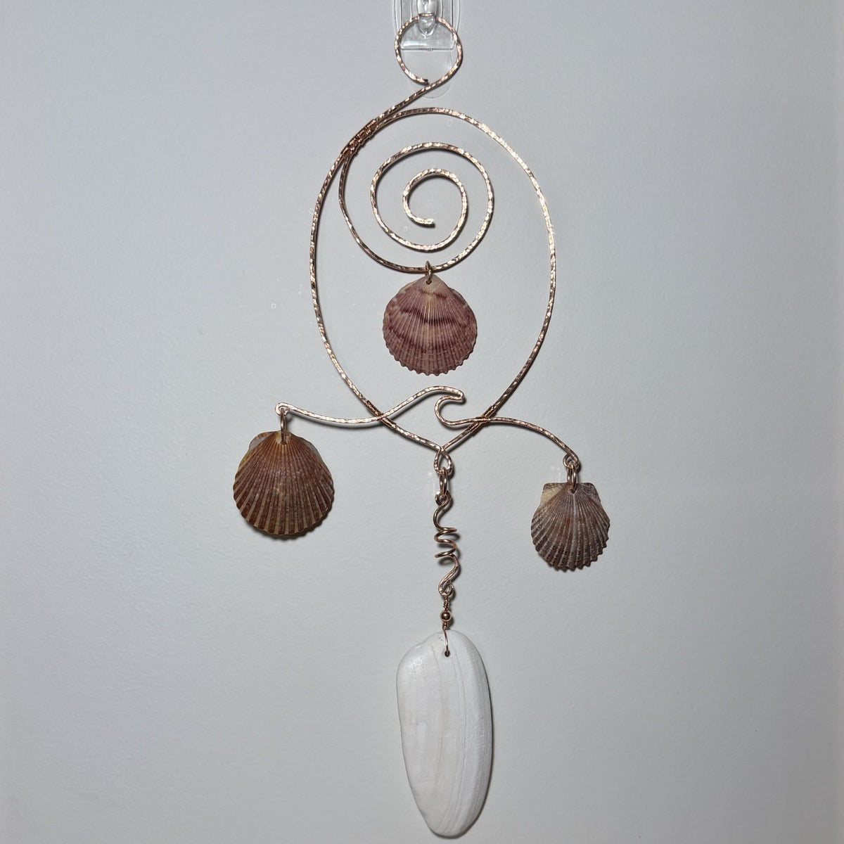 Front view of a shell and hammered copper wire wall/window display piece.